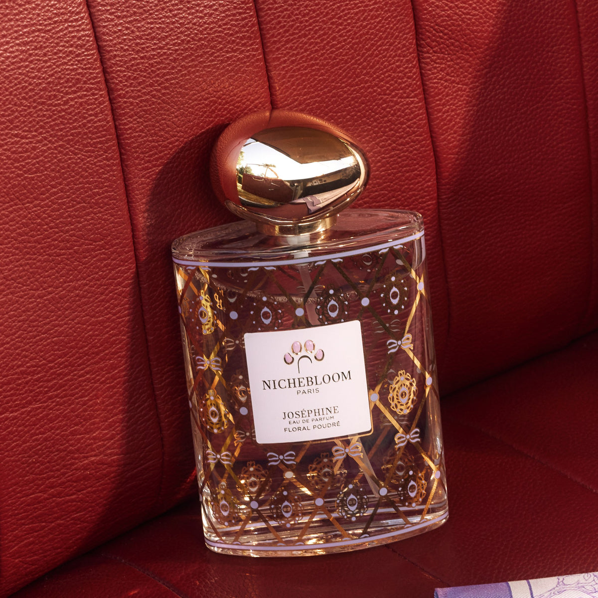 Flacon Joséphine 120 ml sur une banquette en cuir rouge