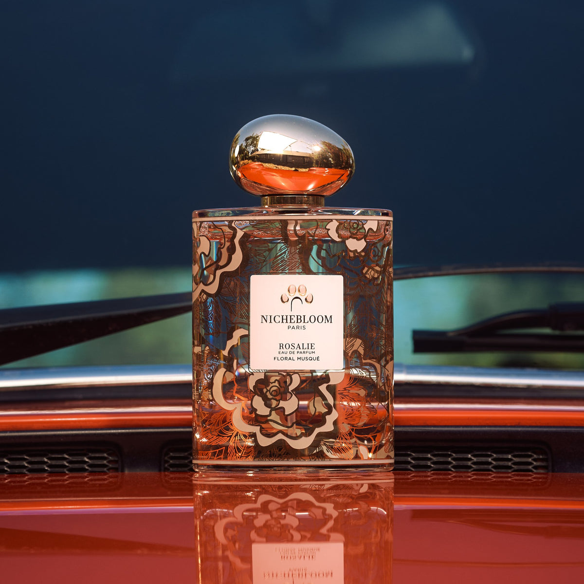 Flacon Rosalie 120 ml sur le capot rouge d'une voiture ancienne